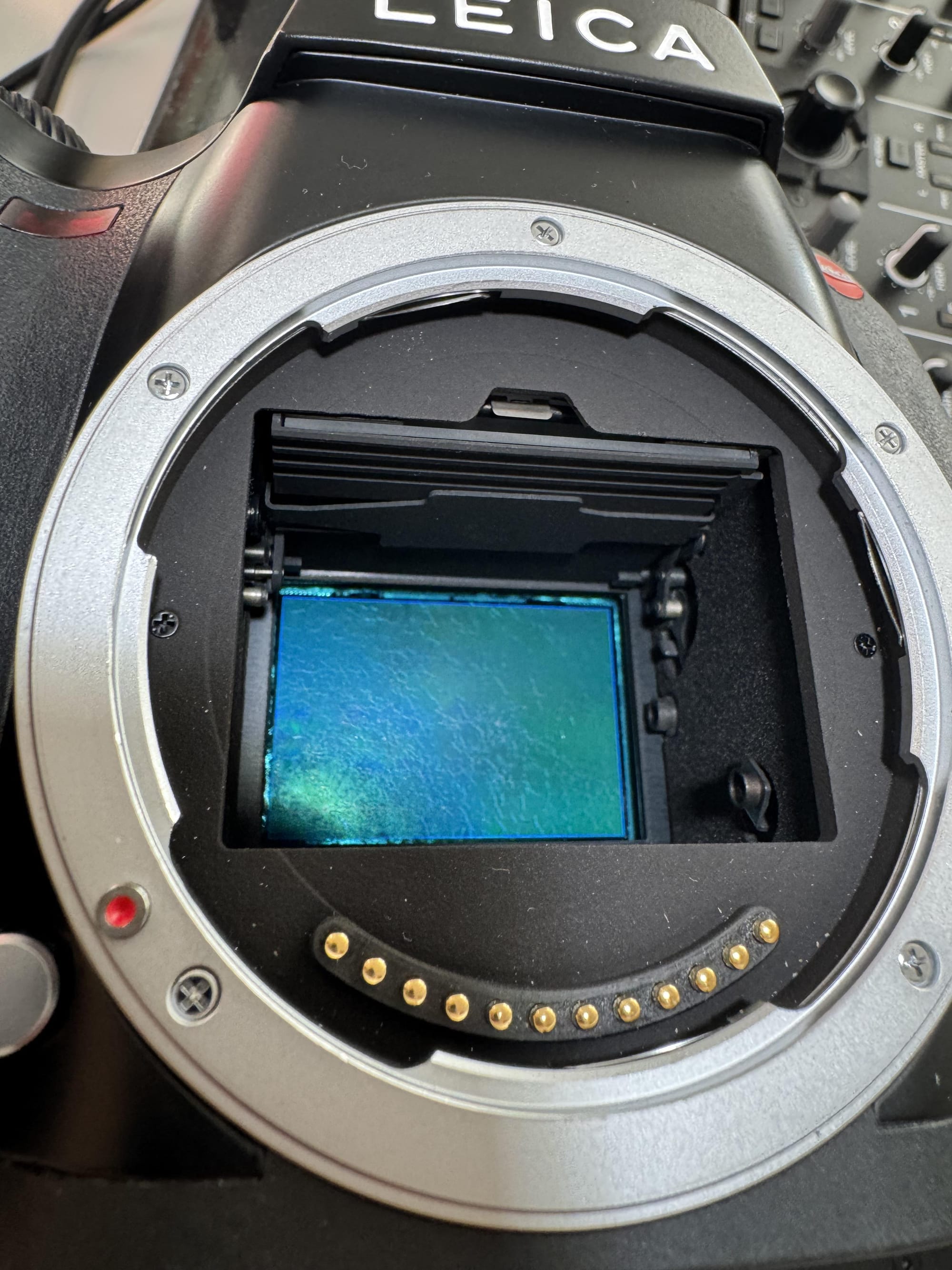 A Leica S camera’s sensor is exposed, showing a green and turquoise sensor with a textured surface. The surface texture is corrosion.
