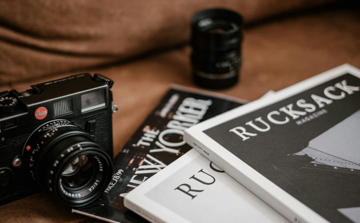 Leica camera on a brown couch next to magazines